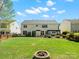 Spacious backyard with a fire pit, pergola-covered patio, and well-manicured lawn at 7822 Noland Woods Dr, Charlotte, NC 28277