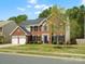 Traditional two-story brick home with a well-manicured lawn, mature trees, and an attached two-car garage at 7822 Noland Woods Dr, Charlotte, NC 28277