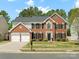 Charming two-story brick home featuring a manicured lawn and a two-car garage, creating a welcoming curb appeal at 7822 Noland Woods Dr, Charlotte, NC 28277