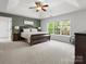 Spacious main bedroom with a tray ceiling, large windows, a ceiling fan, and hardwood floors at 7822 Noland Woods Dr, Charlotte, NC 28277
