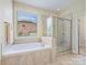 Bright bathroom featuring a soaking tub, glass shower, and a window overlooking the neighborhood at 8618 Whitehawk Hill Rd, Waxhaw, NC 28173