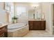 Bright bathroom showcasing a soaking tub, vanity with storage, and natural light from the window at 8618 Whitehawk Hill Rd, Waxhaw, NC 28173