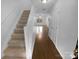 Hallway with staircase featuring hardwood floors and ample lighting, leading to the upper levels of the home at 9930 Birch Knoll Ct, Charlotte, NC 28213