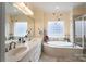 Bright bathroom featuring a soaking tub under a glass block window and dual sink vanity with modern fixtures at 104 Hallmark Xing, Rock Hill, SC 29732