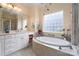 Bright bathroom featuring a soaking tub under a glass block window and dual sink vanity with modern fixtures at 104 Hallmark Xing, Rock Hill, SC 29732