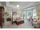 Inviting bedroom featuring tray ceiling, large windows, hardwood floors, and cozy sitting area at 104 Hallmark Xing, Rock Hill, SC 29732
