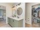 Modern bathroom with double sinks, round mirrors, vanity, and adjacent walk-in closet for efficient storage at 114 Rolling Stone Ct, Mooresville, NC 28117