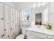 Bathroom with butterfly shower curtain, a white vanity and a silver shelving unit over the toilet at 12305 Stinson Ct, Charlotte, NC 28277