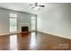 Open living room featuring hardwood floors, fireplace, ceiling fan, and large windows for natural light at 13417 Krislyn Woods Pl, Charlotte, NC 28278