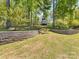 Spacious grassy backyard featuring tiered stone retaining walls with mature trees, offering a private retreat at 1395 Roundstone Rd, Sherrills Ford, NC 28673