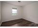 An empty bedroom with light walls and dark wood floors and a window looking out onto a green field at 1663 Smyre Farm Rd # 5, Newton, NC 28658