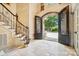 Elegant foyer featuring an arched doorway, iron doors, travertine floors, and a staircase at 20428 Island Forest Dr, Cornelius, NC 28031
