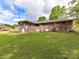Back of the home features a green lawn and brick facade at 225 Enwood Dr, Charlotte, NC 28214