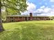 Charming brick home featuring a lush green lawn and meticulously landscaped front yard with mature trees at 225 Enwood Dr, Charlotte, NC 28214
