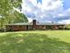 Charming brick home featuring a lush green lawn and meticulously landscaped front yard with mature trees at 225 Enwood Dr, Charlotte, NC 28214