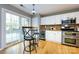 Bright kitchen features a sliding glass door, stainless steel appliances, bar seating, and white cabinetry at 3505 Mayspring Pl, Charlotte, NC 28269