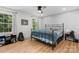 This bedroom boasts wood floors, neutral walls, and a metal bed frame illuminated by natural light from surrounding windows at 4607 Hedgemore Dr # D, Charlotte, NC 28209