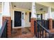 Inviting front porch with black rocking chairs, brick accents and decorative columns enhancing the curb appeal at 5015 Drake Pond Ln, Rock Hill, SC 29732