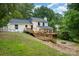 Exterior shot of a white house with a spacious backyard, featuring a wooden deck and a fire pit at 8025 Cliffside Dr, Charlotte, NC 28270