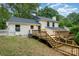 Exterior shot of a white house with a dark roof, wood deck, and stairs leading to the backyard at 8025 Cliffside Dr, Charlotte, NC 28270