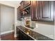 A stylish bar area with dark wood cabinets, wine rack, glassware storage, and a black marble countertop at 10643 Rippling Stream Nw Dr, Concord, NC 28027