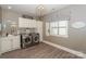 Bright laundry room with stainless steel washer and dryer, storage cabinets, and wood-look flooring at 10643 Rippling Stream Nw Dr, Concord, NC 28027