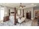 View of the main bedroom featuring a four poster bed, a seating area, and a large dresser at 10643 Rippling Stream Nw Dr, Concord, NC 28027