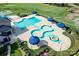 Aerial view of the community pool with unique design, blue umbrellas, and surrounding greenery at 10643 Rippling Stream Nw Dr, Concord, NC 28027