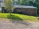 Backyard view featuring a wooden deck attached to the brick house, surrounded by green lawn and trees at 1300 Irish Potato Rd, Concord, NC 28025