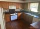 Galley kitchen features wood cabinets, laminate countertops, white appliances, and hardwood floors at 1300 Irish Potato Rd, Concord, NC 28025