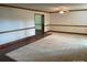 An empty living room with light-colored carpet, wood trim, and a connecting hallway at 1300 Irish Potato Rd, Concord, NC 28025