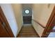 Long carpeted staircase leading down, illuminated by a small octagonal window at 1300 Irish Potato Rd, Concord, NC 28025