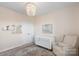 Adorable Bedroom featuring a white crib, neutral armchair, and elegant chandelier lighting at 1519 Cedar Park Dr, Pineville, NC 28134