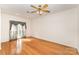 Bright bedroom featuring hardwood floors, a ceiling fan, and a large window with decorative curtains at 1801 Briarcrest Nw Dr, Charlotte, NC 28269