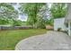 Wide backyard with mature trees and a concrete patio extending to a wood fence and shed, offering privacy at 22025 Torrence Chapel Rd, Cornelius, NC 28031