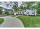 A view of the home's exterior, featuring a well-kept lawn, driveway, and lush surrounding trees at 22025 Torrence Chapel Rd, Cornelius, NC 28031