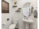 Stylish half-bathroom features modern fixtures, pedestal sink, round mirror, and decorative wall art and shelves at 4538 Opus Ln, Charlotte, NC 28214