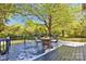 View of the outdoor deck area featuring a dining table and seating, nestled beneath a large tree at 4937 Broken Saddle Ln, Charlotte, NC 28226
