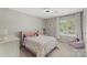 Bright bedroom with a pink bed, white dresser, and a window with outside views at 6605 Point Comfort Ln, Charlotte, NC 28226