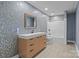 Basement bathroom with wooden cabinet, modern fixtures, shower, and eye-catching mosaic-style tile wall at 6743 Fox Ridge Cir, Davidson, NC 28036