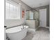 Bright bathroom featuring a standalone tub, a glass-enclosed shower, and stylish fixtures on gray tile flooring at 6743 Fox Ridge Cir, Davidson, NC 28036