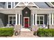 Inviting front porch with a red door, stone pillars, white trim, chairs, plants, and brick steps at 6743 Fox Ridge Cir, Davidson, NC 28036