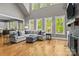 Bright living room with hardwood floors, comfortable sofa, large windows, and a partial view of the kitchen at 6743 Fox Ridge Cir, Davidson, NC 28036