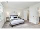 Well-lit bedroom featuring a platform bed, neutral carpet, white trim, and a comfortable seating area at 8221 Pineville Matthews Rd # A, Charlotte, NC 28226