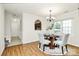 Cozy dining area with wood floors, chandelier, and views into the kitchen via arched serving space at 8221 Pineville Matthews Rd # A, Charlotte, NC 28226