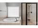 Bright bathroom featuring a soaking tub, and a tiled shower with a glass door at 9008 Skipaway Dr, Waxhaw, NC 28173