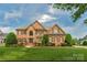Traditional two-story brick home with well-manicured lawn, mature trees, and shuttered windows at 9008 Skipaway Dr, Waxhaw, NC 28173