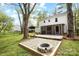 Backyard view with a fire pit, white home with a screened porch, and trees at 9319 Harps Mill Ct, Charlotte, NC 28270