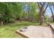 Backyard featuring a fire pit and wood fencing amongst mature trees and green grass at 9319 Harps Mill Ct, Charlotte, NC 28270