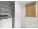 Bright laundry room features a washer and dryer, storage shelves, and white door with a bamboo shade at 9319 Harps Mill Ct, Charlotte, NC 28270